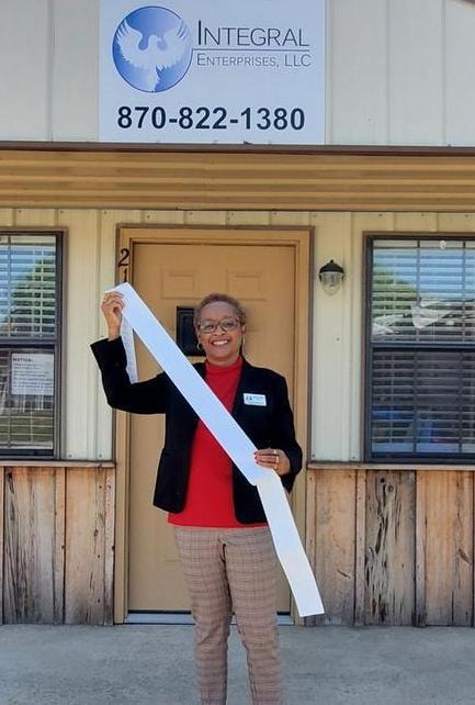 Sandra Collins standing in front of the Integral Enterprises LLC office holding a ribbon